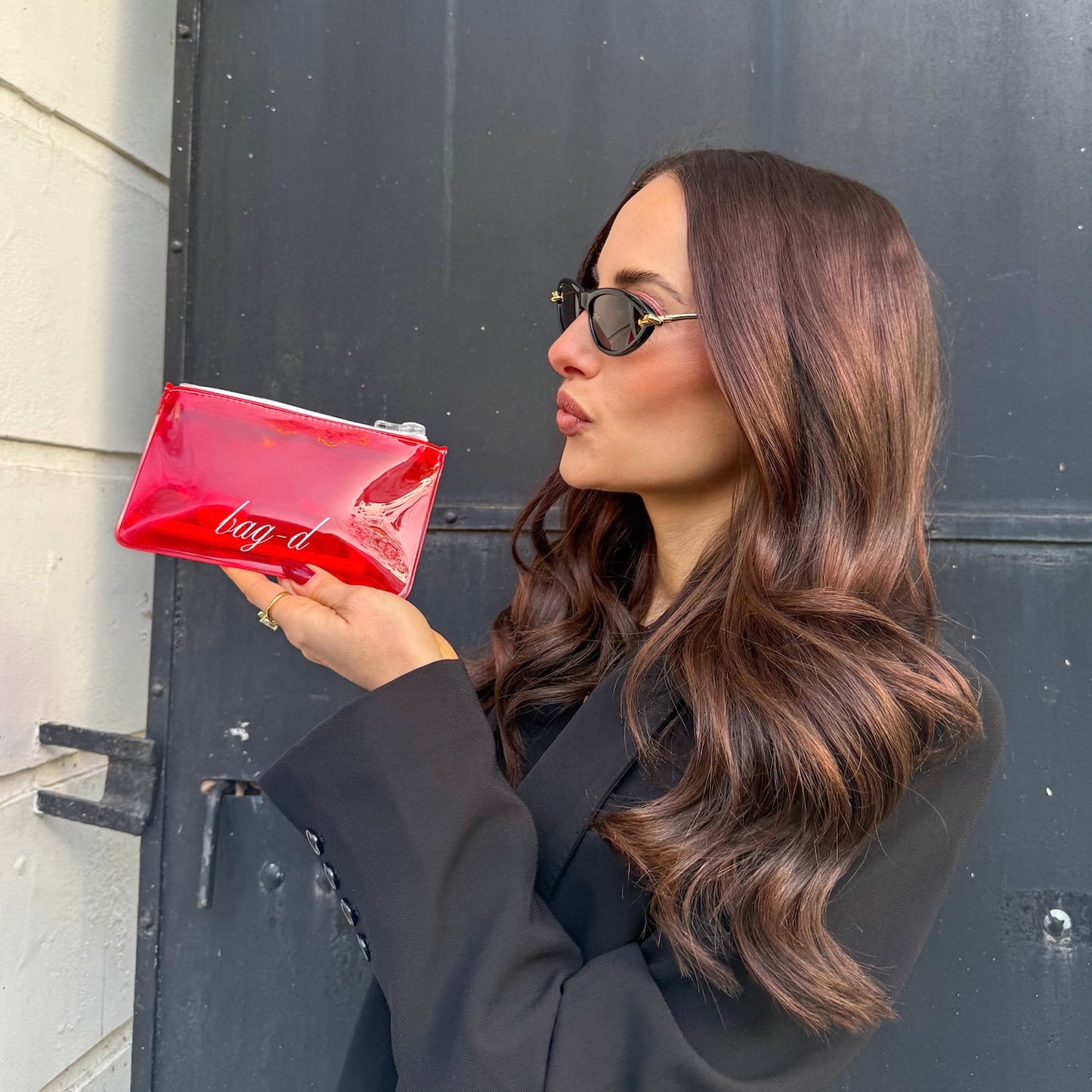 model holds bagd_everything_pouch_red_tpu_ with lipstick inside